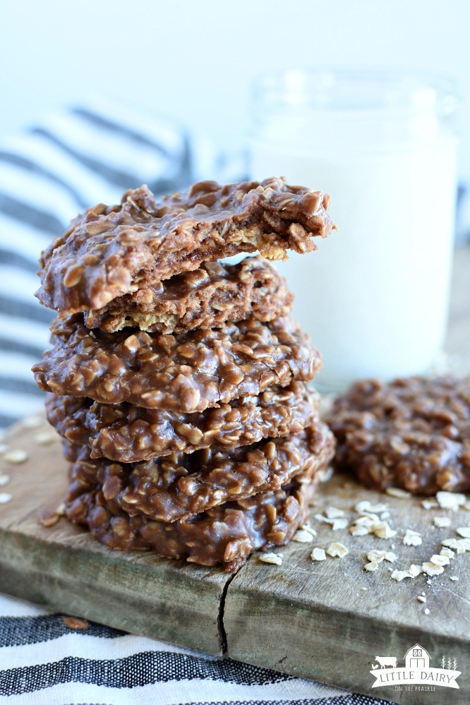 a stack of peanut butter no bake bake cookies, a jar of milk, the top cookie has a bite taken out of it