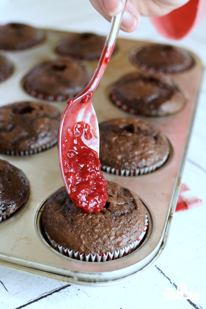 Chocolate cupcakes with a spoon filling with red raspberry sauce