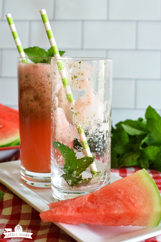 An empty glass with mint leaves and a straw, a full glass of watermelon lemonade behind it