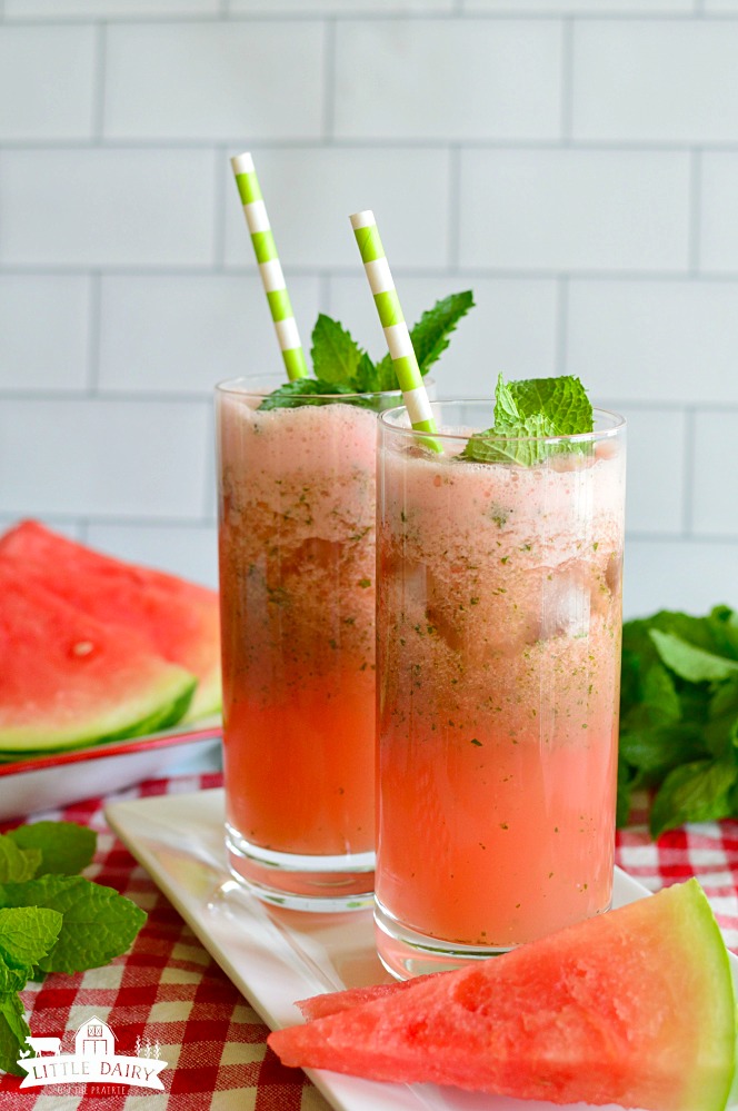 Two glasses of red watermelon lemonade with foam on top, and a straw