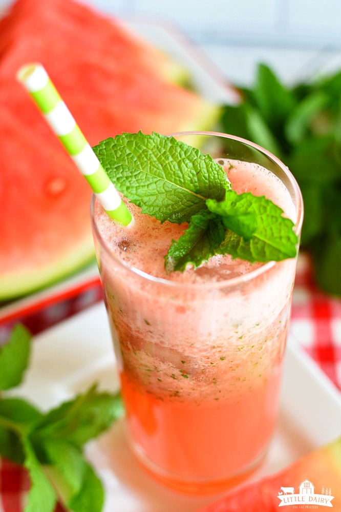 Top view of red watermelon lemonade with a mint sprig and a green and white straw