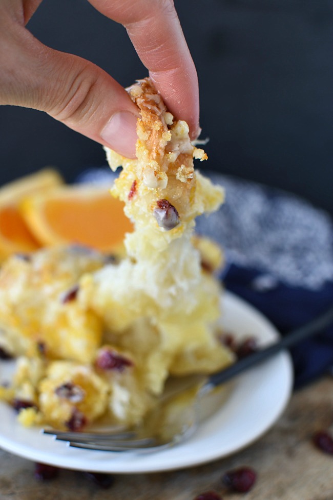 fingers pulling a piece of cranberry orange monkey bread from the plate