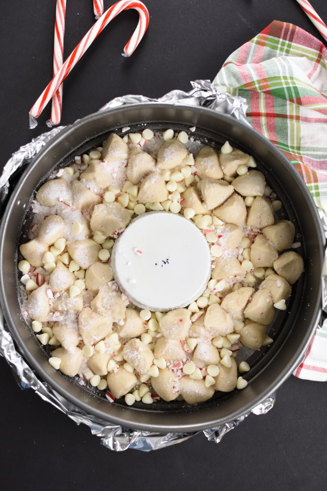 unbaked rolls in a springform pan with crushed candy canes and white chcolate chips