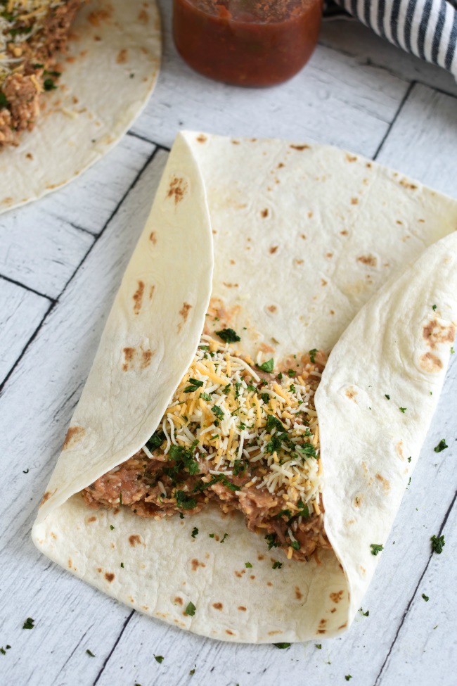 A flour tortilla with shredded beef, beans, and cheese
