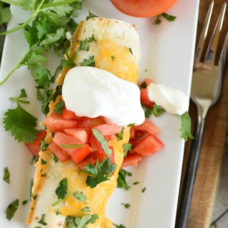 Shredded Beef and Bean Burrito topped with cheese, tomatoes, cilantro, and sour cream