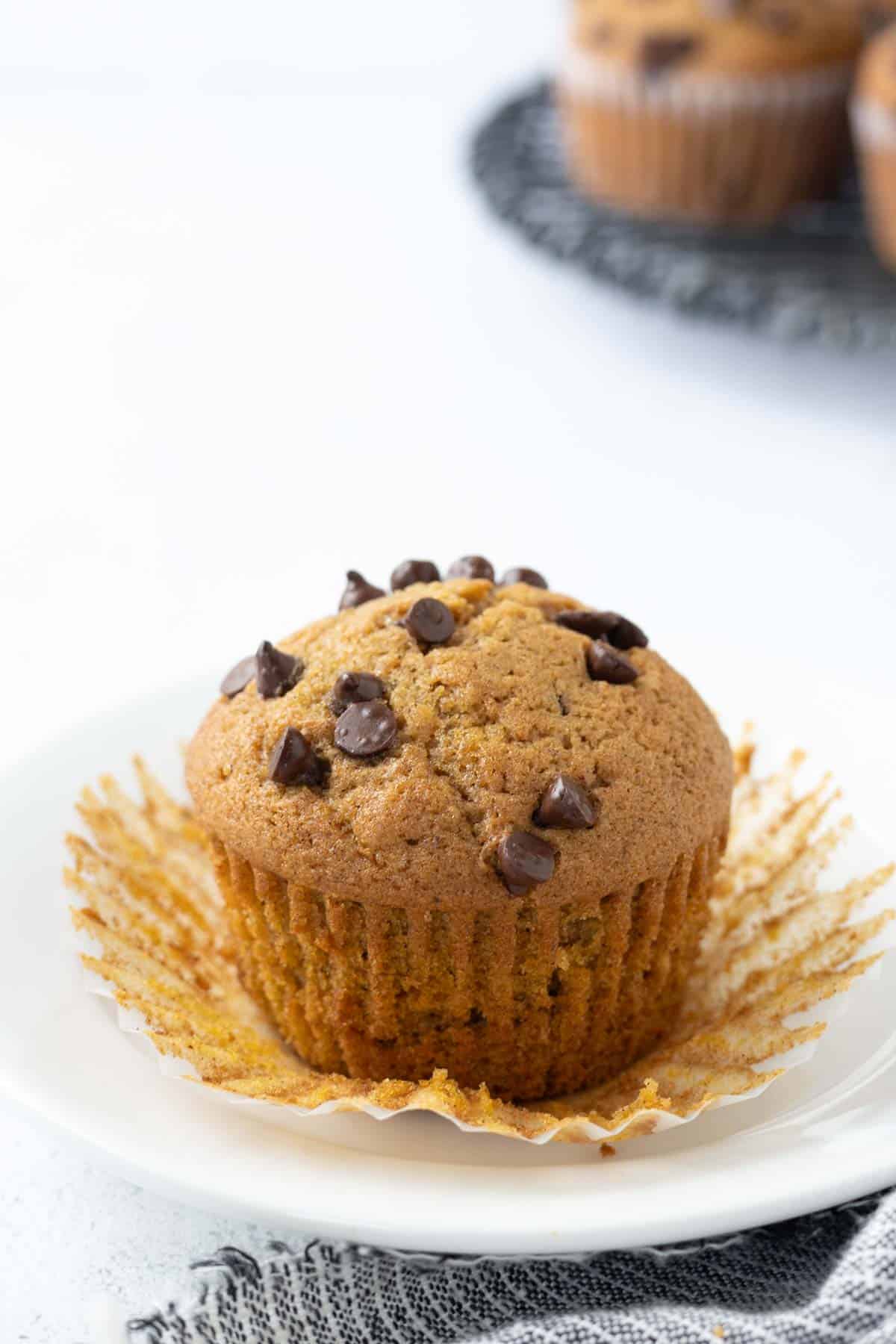 A chocolate chip pumpkin zucchini muffin in the paper muffin wrapper.