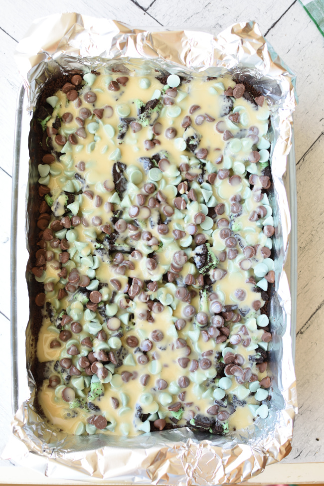 magic bars in a pan with sweetened condensed milk on top