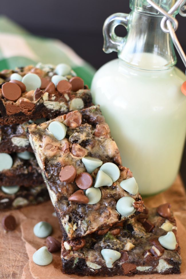 Mint Chocolate Magic Bar Cookies on a board with a container of milk and mint chocolate sandwich cookies