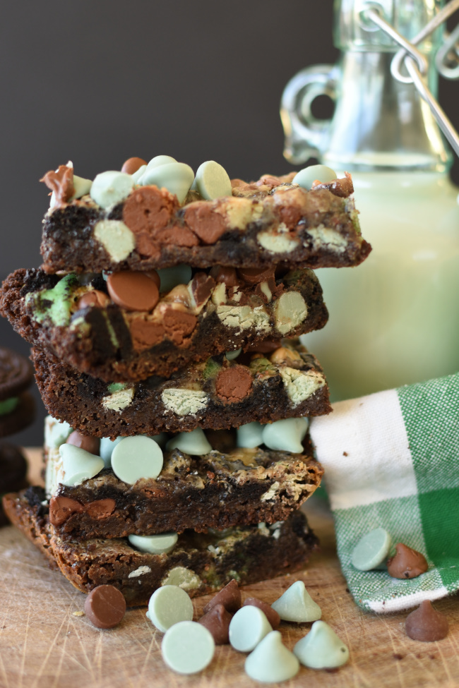 A stack of mint chocolate magic bars with a container of milk and a green and white napkin