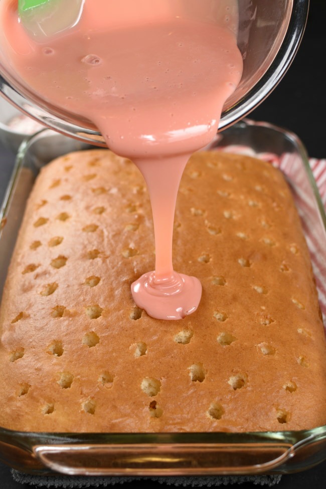 white cake mix with holes, and pink sweetened condensed milk drizzled on top