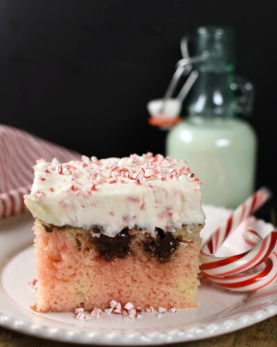 Piece of white poke cake with pink marbeling, chocolate, and cheescake topping