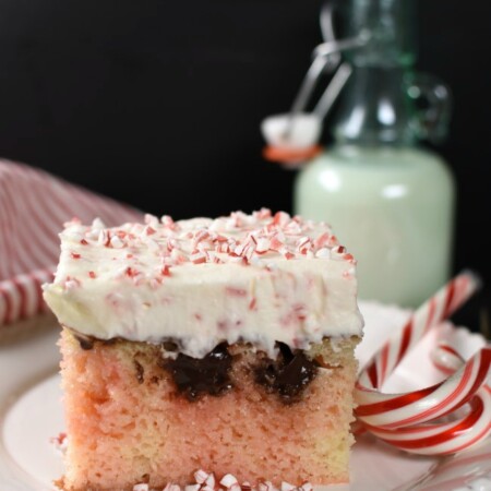 Piece of white poke cake with pink marbeling, chocolate, and cheescake topping