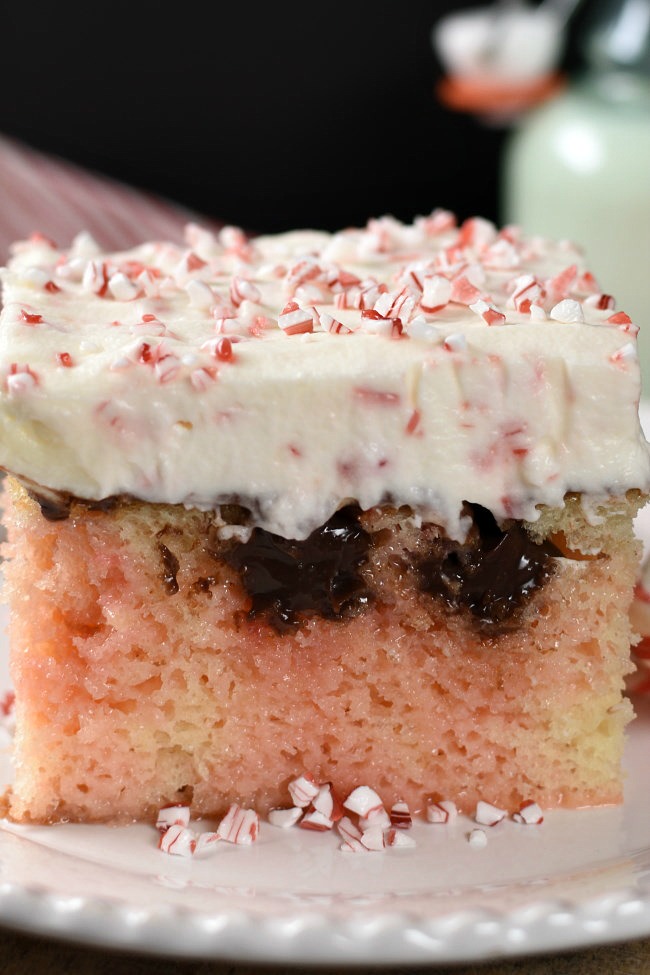 Piece of white poke cake with pink marbeling, chocolate, and cheescake topping