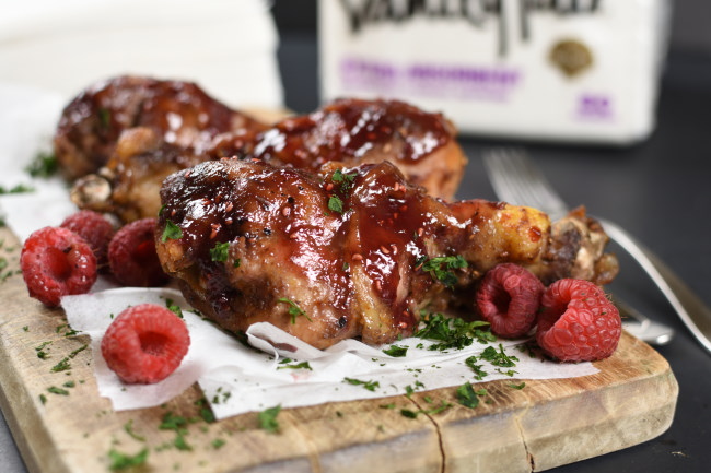 chicken drumsticks and raspberries on a wood board