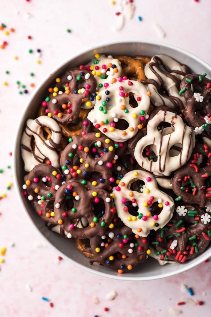 a bowl filled with chocolate covered pretzels and colorful sprinkles
