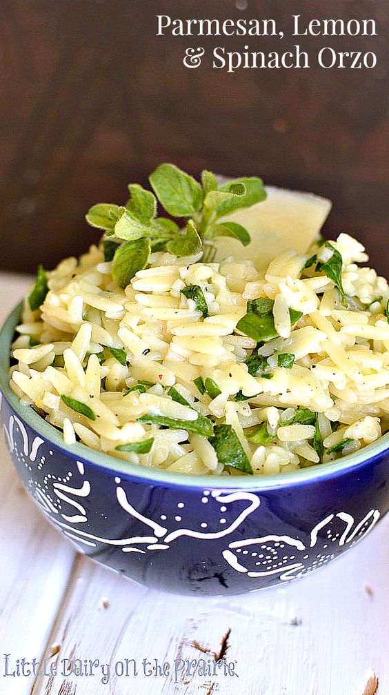 a blue bowl with cooked orzo with chopped spinach in it