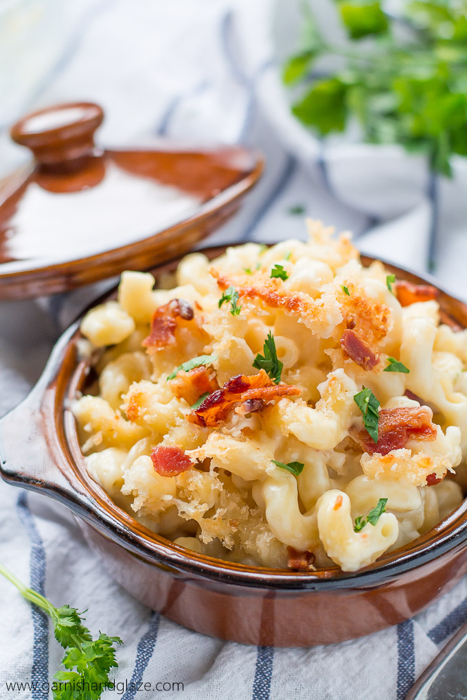 a brown serving dish with baked mac and cheese topped with panko crumbs, bacon, and chopped parsley