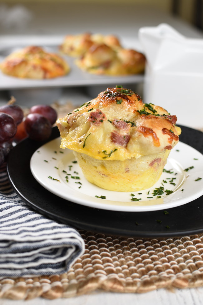 baked breakfast monkey bread with ham on a white plate with parsley sprinkled over the top