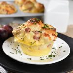 baked breakfast monkey bread with ham on a white plate with parsley sprinkled over the top