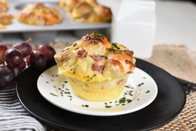 baked breakfast monkey bread with ham on a white plate with parsley sprinkled over the top