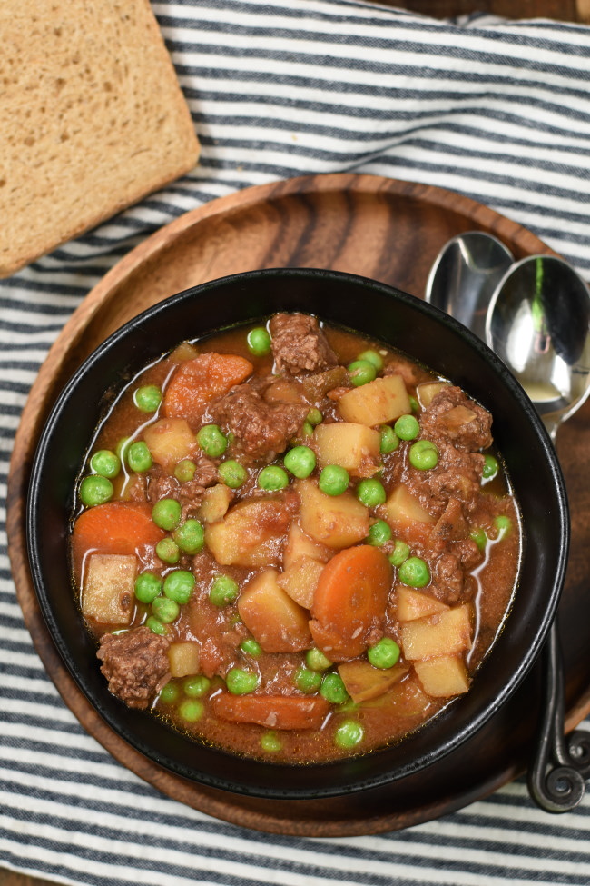 Slow cooker stew in a black bowl on a striped napkin