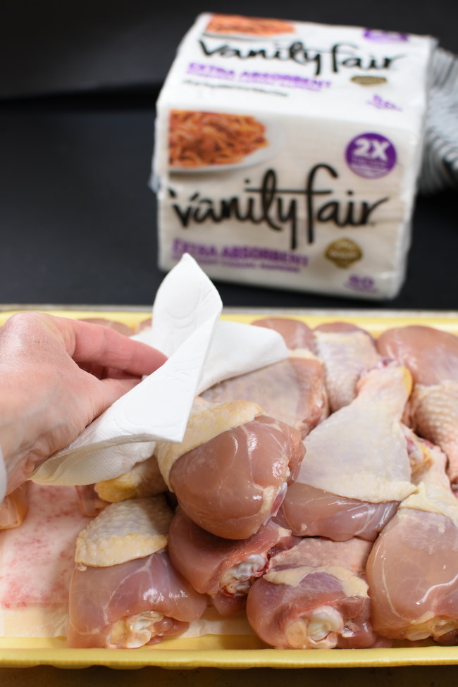 patting chicken drumsticks dry with a napkin