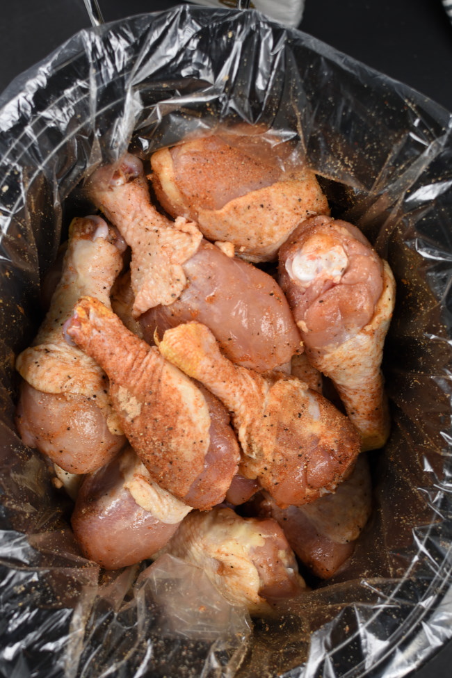 a slow cooker with raw chicken drumsticks