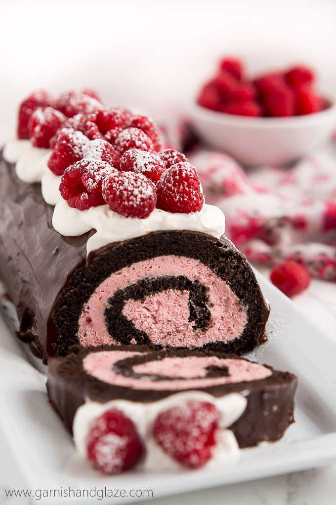 a chocolate cake roll with raspberry cream rolled inside, buttercream and fresh raspberries on top