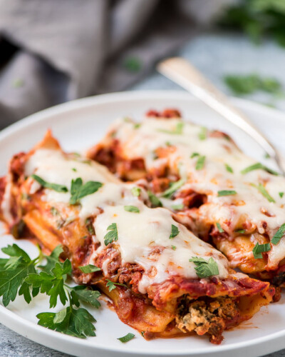 two baked beef manicotti with grated cheese and chopped parsley