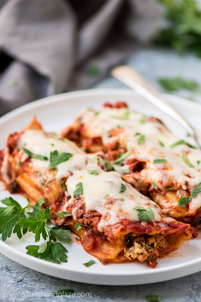 two baked beef manicotti with grated cheese and chopped parsley