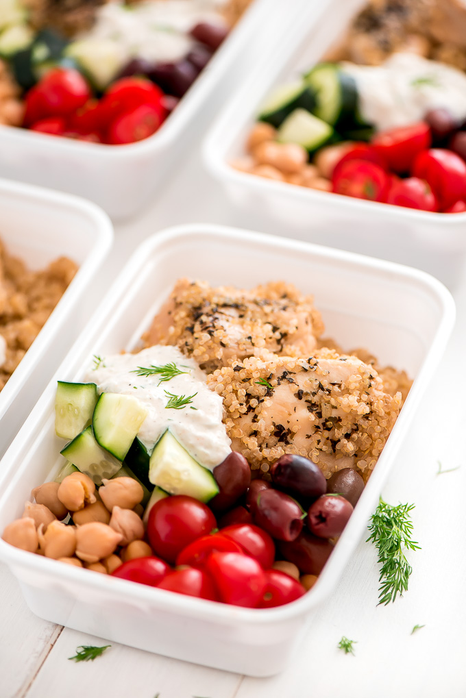 square plastic storage containers with tomatoes, chickpeas, chicken, cucumbers, olives and quinoa