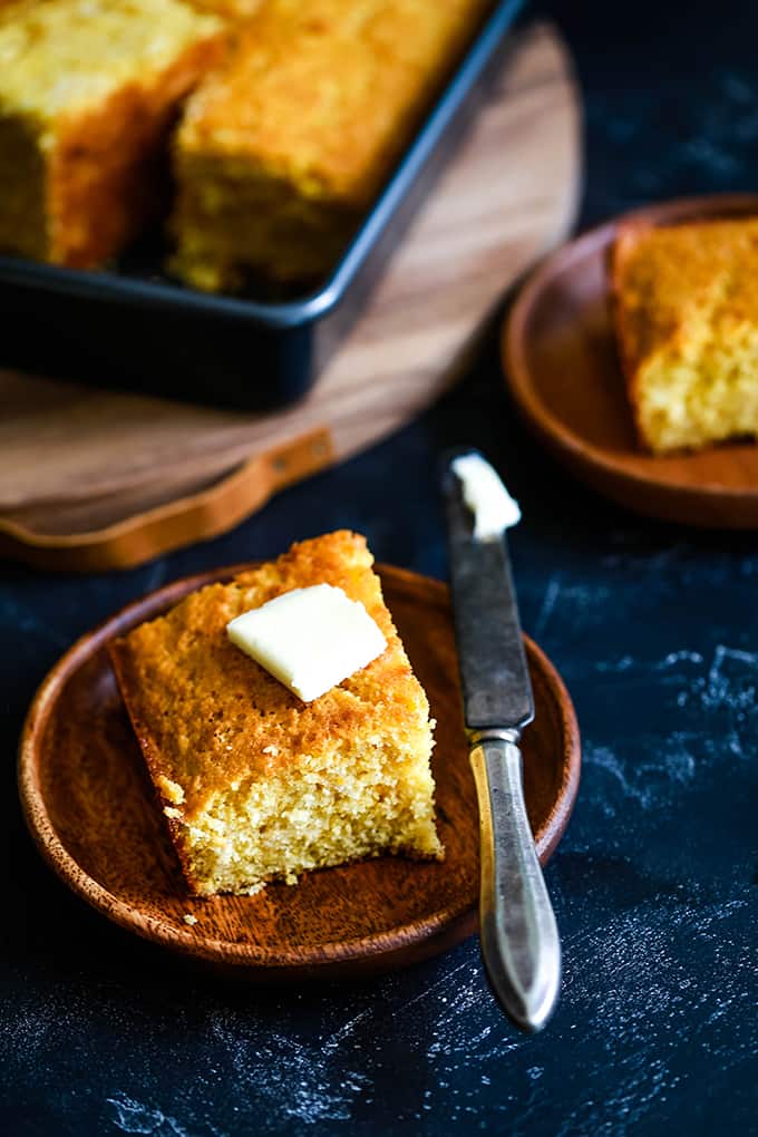 a square of baked cornbread with a pat of butter on top