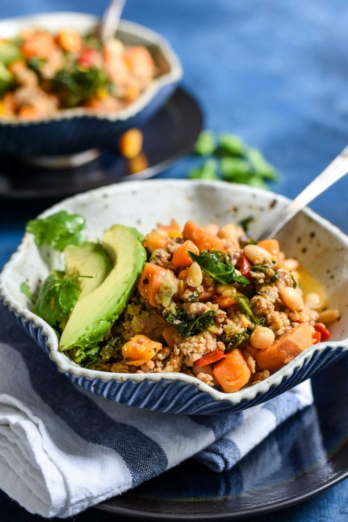 A blow of chili with avocados on top