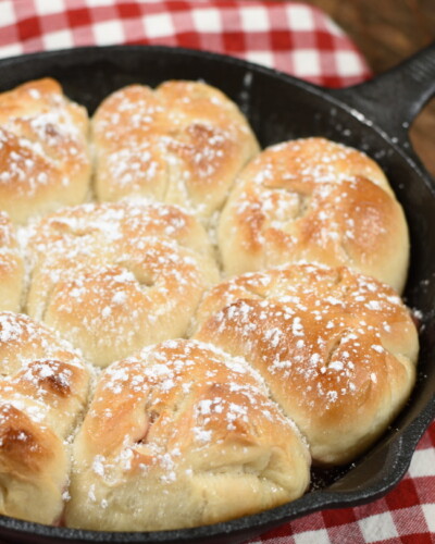 Baked Cherry Cheesecake Monkey bread, dusted with powdered sugar in a cast iron skillet