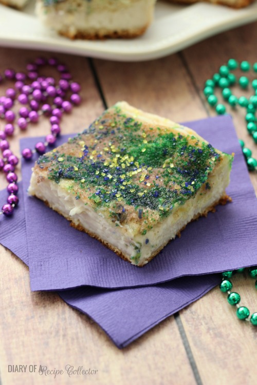 a crescent roll cheesecake square sprinkled with purple and green sugar, on a purple napkin decorated with beads