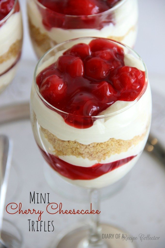 a glass goblet with layers of cheesecake, graham cracker crumbs, and cherry pie filling
