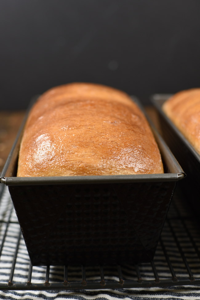 golden brown, baked whole weaht bread in a black loaf pan