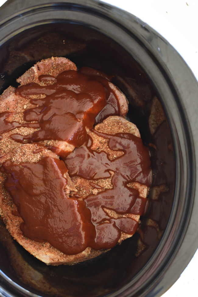 pork chops drizzled with barbecue sauce in a slow cooker