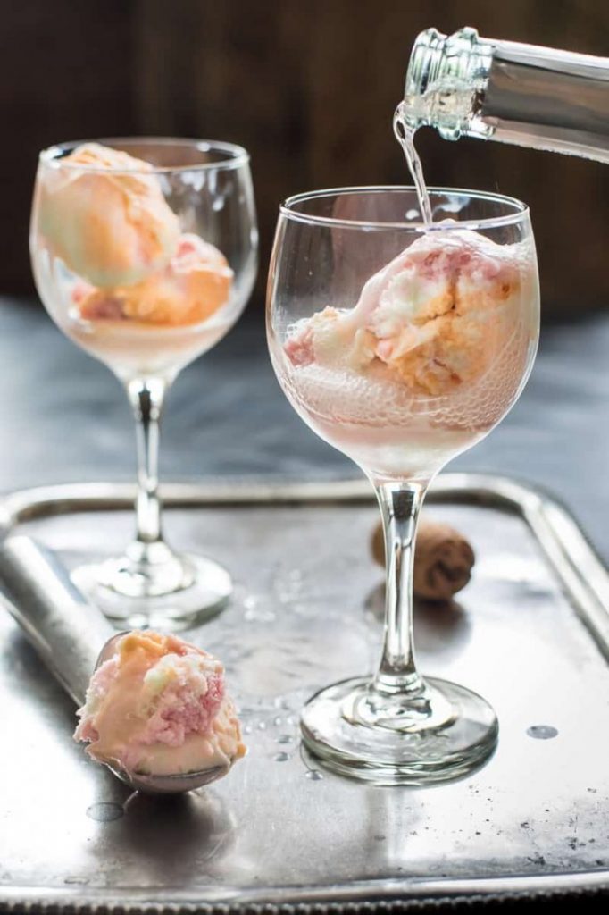 two wine glasses filled rainbow sherbet and being filled with champagne