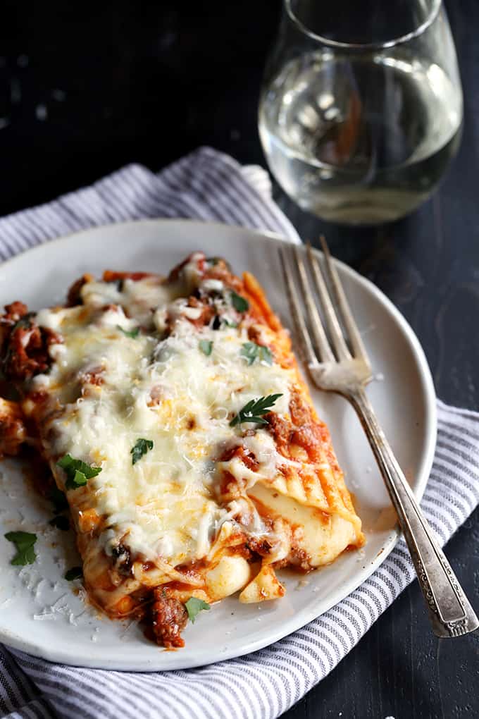 manicotti on a plate with melted mozzarella cheese sprinkled with parsley