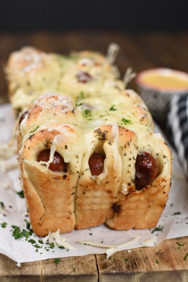 a loaf of baked pull apart bread made with little smokies and cheese melted on top