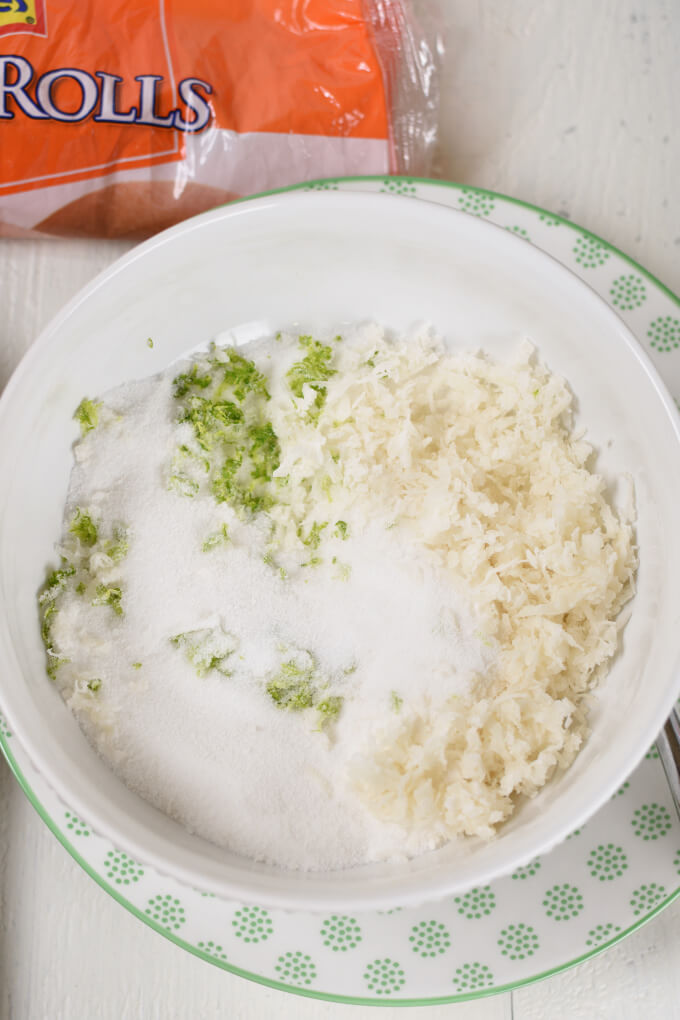 a white bowl with sugar, lime zest, and shredded coconut