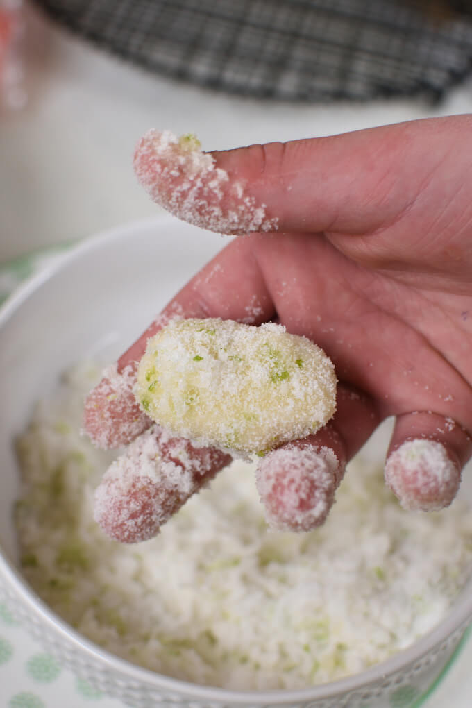 a hand holding a ball of dough rolled in sugar mixture