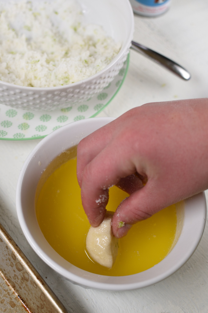 a hand dipping a piece of dough in melted butter
