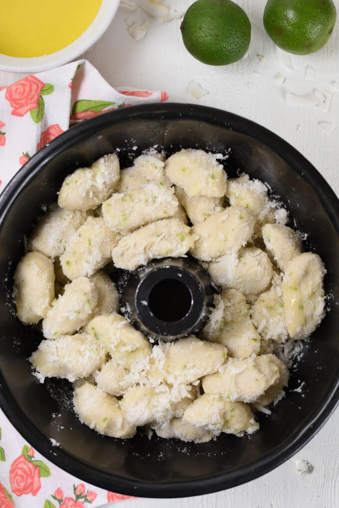 balls of dough tossed in coated in a sugar mixture in a black bundt pan
