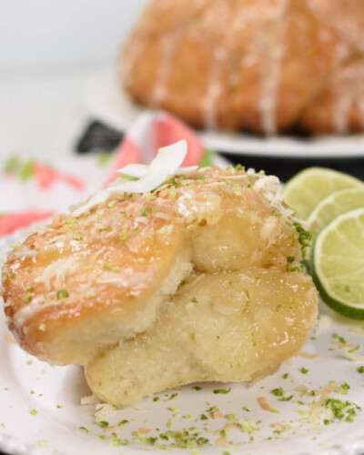 a serving of pull apart bread on a plate sprinkled with lime zest and coconut, garnished with lime slices