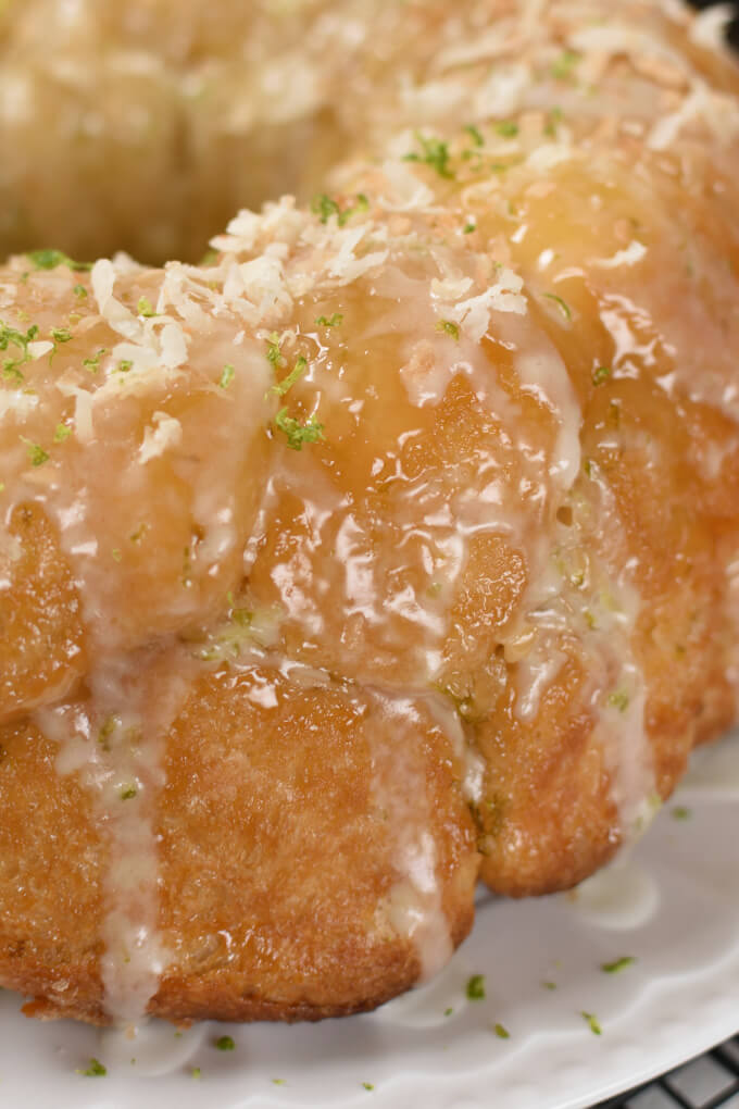 a close up image of baked and glazed monkey bread sprinkled with toasted coconut and lime zest