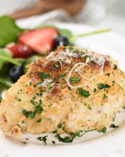 a baked breaded chicken breast topped with grated parmesan cheese and chopped parsley