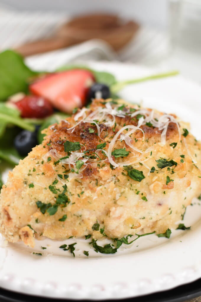 a baked breaded chicken breast topped with grated parmesan cheese and chopped parsley