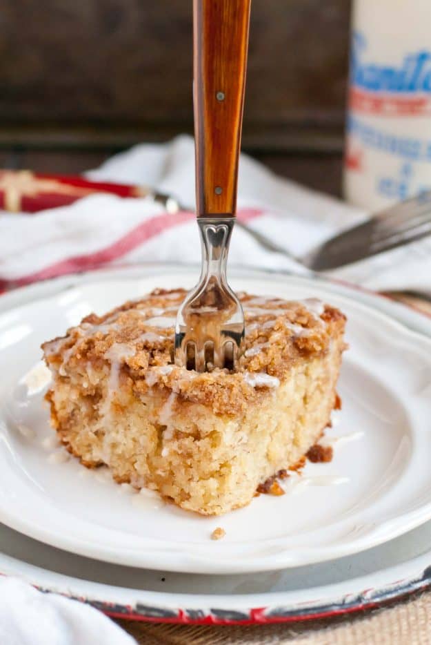 a square of banana crumb cake on a plate with a fork stuck in it